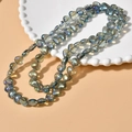 Macro detail of iridescent heart-shaped glass beads with colorful metallic luster - Blue Green Heart