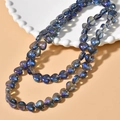 Close-up of heart-shaped glass beads with iridescent blue aurora borealis coating on a dish - Blue Purple Heart