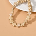 Macro shot of pearlized cream star-shaped ceramic beads on a white textured ceramic dish - Milk Coffee
