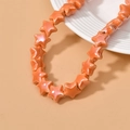 Macro shot of bright orange star-shaped ceramic beads with a lustrous pearlescent finish - Orange Red