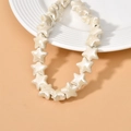 Close-up of cream star-shaped ceramic beads with pearl luster on a white plate - Beige