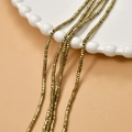 Macro detail of 2mm faceted gold-plated hematite square beads on a decorative ceramic plate - Light Gold (22#)
