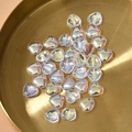 Makroaufnahme von 10mm schillernden Herzglasperlen auf einem goldenen Tablett - 10mm / Aurora Transparent Mehrfarbig