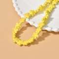 Macro shot of yellow five-petal ceramic flower beads on a white scalloped plate - Yellow