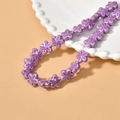 Detailed view of lavender ceramic flower beads for DIY jewelry making on white scalloped plate - Purple