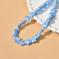 Close-up of light blue ceramic flower beads on a white tray for DIY jewelry making - Peacock Blue