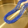 Detalle macro de collares de varias capas con cuentas de ojo de gato azul de 2mm en bandeja - Azul Zafiro