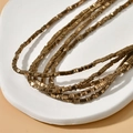 Close-up of bronze gold triangular hematite beads on a white textured stone surface - 1 Strand (Approx. 350 Pcs) / 3# Bronze Triangle