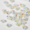 Dettaglio macro di perle di vetro a forma di foglia con macchie artistiche a pittura a olio - Giada Punti Colorati