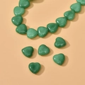 Macro detail of heart-shaped green natural stone beads with polished finish for DIY jewelry - Peacock Green Heart