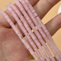 Vue détaillée de perles cylindriques en quartz rose tenues en main pour visualiser la taille - Style Cylindrique (22#) / 4*4mm (Env. 95 Perles/Fil) / Quartz rose