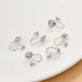 Close-up of silver screw-back earring clips for DIY jewelry making on white base - White Gold Bead Style