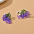Orecchini a fiore fatti a mano con perle viola e dettagli verdi su sfondo neutro - Fiore di Farfalla Viola