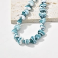 Macro shot of heart-shaped glass beads with blue and white marble texture on stone - Lake Blue Heart