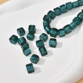 Macro detail of 8mm teal square glass beads with silver foil and brushed texture for DIY - Lake Green