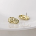 Detailed close-up of golden irregular oval earrings with hammered texture and flower relief - 19*9mm / Gold Floral