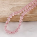 Detail shot of 6mm rose quartz beads with natural textures on a rustic wooden background - Rose Quartz (30#) / 10mm (Approx 38pcs/Strand)