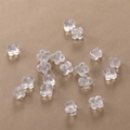 Transparent flower-shaped silicone earring backs in bulk on a golden brushed surface - 10 Pack (Approx 5.4*4mm) / Clover Transparent Style (2B-130)