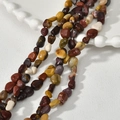 Close-up of irregular earth-toned natural gemstone beads on a white ceramic plate - Irregular Chips (30#) / 1 Piece / Yellow Jasper