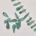 Close-up of raw natural green quartz crystal points on a strand for jewelry making - Green