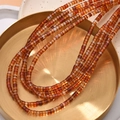 Close-up of cylindrical red agate stone beads on a gold metal tray for jewelry making - Red Agate Style (24#)