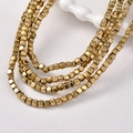 Macro detail van 3mm gouden hematiet kubuskralen voor DIY sieraden en kralenwerk - Lichtgouden Kubus