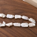Close-up of irregular rectangular baroque pearls with natural luster on a wooden surface - One Strand (Approx Beads)
