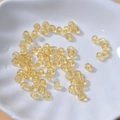Transparente bernsteinfarbene 4mm Glasperlen in einer weißen Schale für DIY-Schmuck - Hellgelb