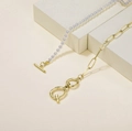 Minimalist gold link chain and pearl necklace with toggle clasp on beige background - Letter Q
