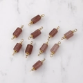 Dettaglio macro di ciondoli in quarzo fragola con cappucci floreali placcati in oro 14K per gioielli - Quarzo rosa