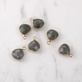 Detailed view of faceted heart-shaped grey natural stone pendants with gold metal edges - Gold Edged Labradorite
