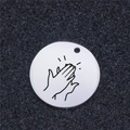 Macro view of a round stainless steel charm with a black engraved hand clapping design - Applause Gesture (AL332)