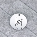 Macro shot of circular stainless steel pendant featuring laser-engraved hand sign - Rock On Gesture (AL339)