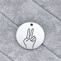 Macro shot of a stainless steel round pendant with engraved hand gesture sign on plush fabric - Victory Gesture (AL343)