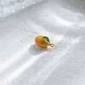 Vista macro de un pequeño colgante de naranja con hoja verde y aro de metal dorado - Estilo Naranja (TZ-TP1002-02-yellow)