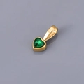 Macro shot of a heart-shaped green gemstone pendant with polished gold plating - May