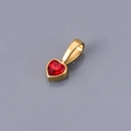 Close-up of heart-shaped gold pendant with vibrant red crystal on reflective surface - January