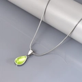 Macro-opname van groene edelsteen hanger aan een zilveren slangenketting sieraad - Zilver-Groen