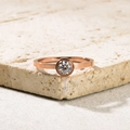 Macro-opname van een 18k roségoud vergulde ring met zirkonia op een stenen basis - US 5 / Minimalistische Stijl Met Eén Steen (J12)