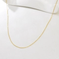 Macro detail of adjustable gold cable chain necklace on a clean white ceramic background - Calendered Chain