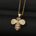 Gouden bijen hanger ketting met zwarte en witte zirkonia op zwarte textuur achtergrond - Kristallen Vleugels Bij Stijl (DX21)