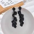 Macro detail of long black matte petal drop earrings on a minimalist display tray - Black (Style A)
