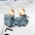 Detailed close-up of golden oval studs and blue-grey matte resin flower petal earrings - Gray