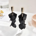 Macro shot of tiered black matte petal pendant earrings with gold connectors on a card - Black