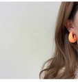 Detail of bright orange matte C-shaped hoop earrings worn by a model on light background - Bright Orange (A318)