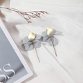 Detailed close-up of matte grey flower petal earrings with golden round accents on silk - Gray