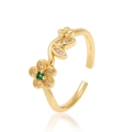 Anillo de flor dorado ajustable con piedras verdes y blancas sobre un fondo blanco - Flor de Cinco Pétalos de Diamante de Corazón Verde