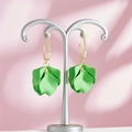 Macro shot of green petal earrings with golden hexagon studs on a pink display stand - Light Green Style (A1176)