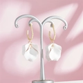 Detail of white matte petal earrings with golden hexagonal hooks on a silver T-stand display - White Style (A1177)