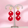 Detail view of red petal earrings with pearls on a silver display stand with silk background - Vibrant Red (A1395)